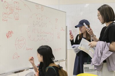 two students watched a mobile phone and a student wrote on a white board