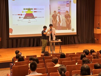 Two students at the stage talking to the audience
