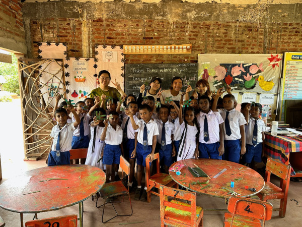 HKU students teaching the Sri Lankan students how to make a fish toy using coconut leaves.